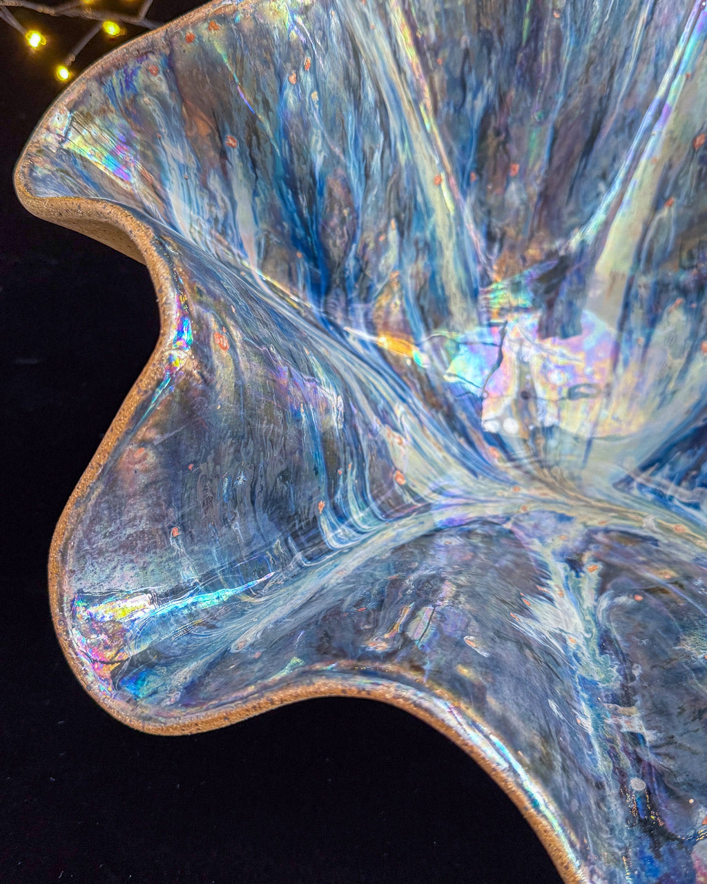 Ruffled edge of a hand built stoneware bloom sculpture with bare clay rim