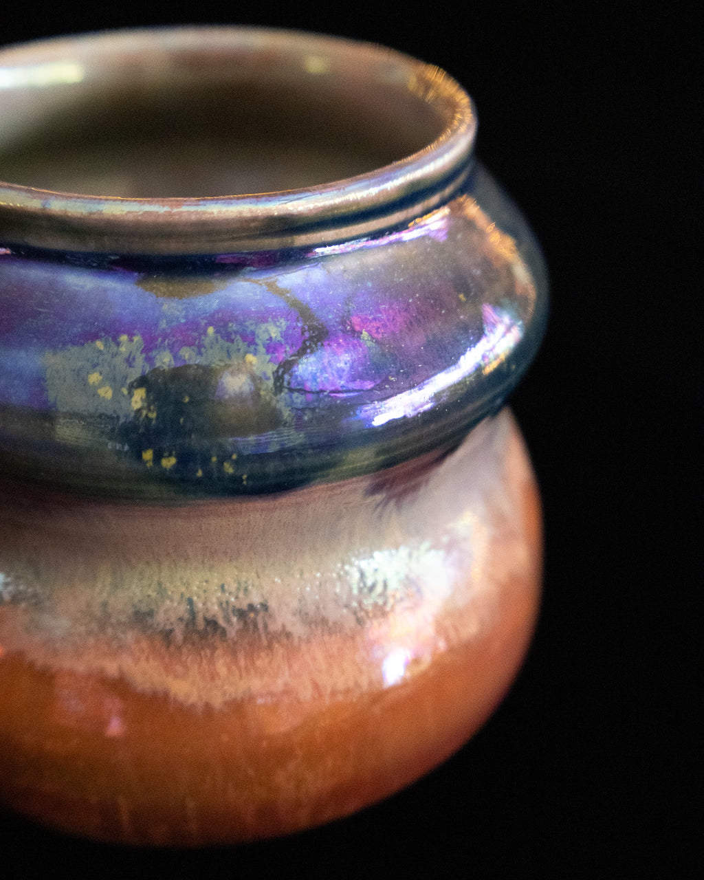 Close detail of blue and copper luster glaze meeting on handmade pottery