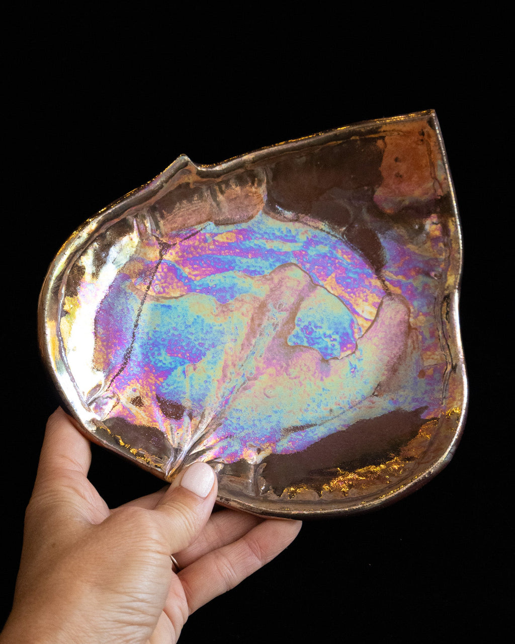 Handmade leaf plate held sideways showing the pressed veining and warm amber rim