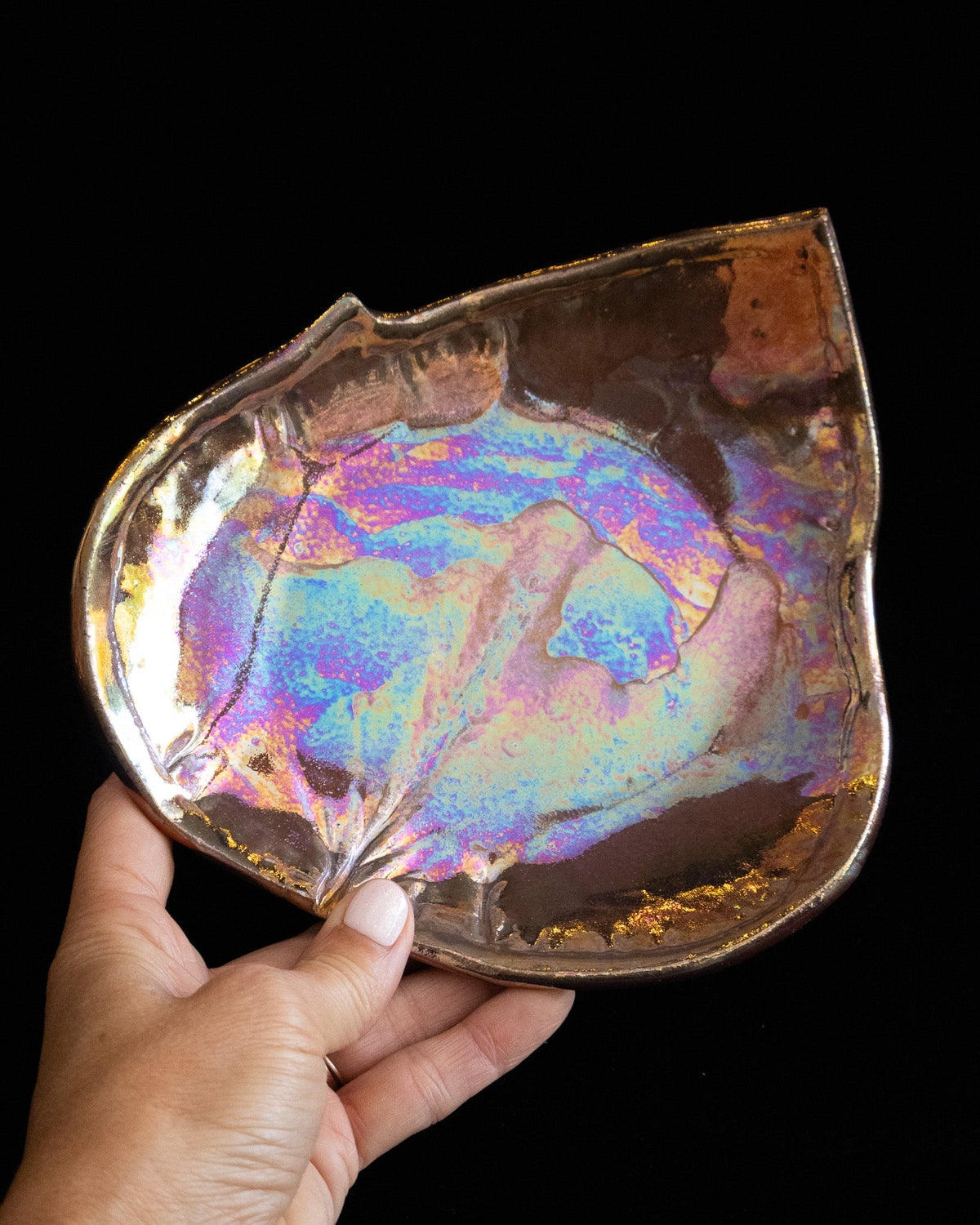 Handmade leaf plate held sideways showing the pressed veining and warm amber rim