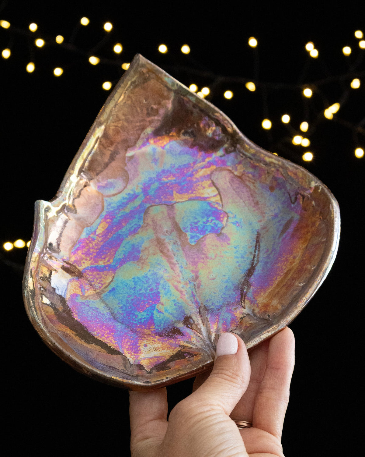 Angled view of an iridescent leaf shaped ceramic keepsake plate