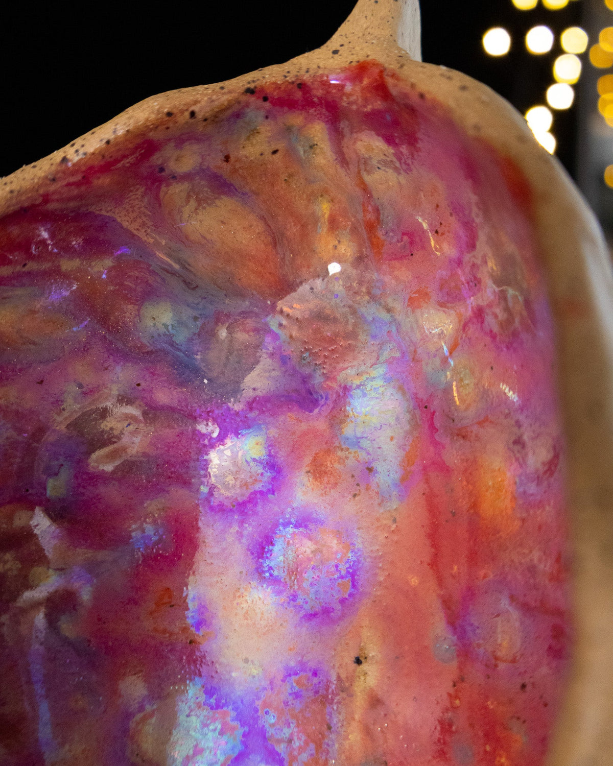 Close detail of magenta and violet in-glaze luster inside a seed pod