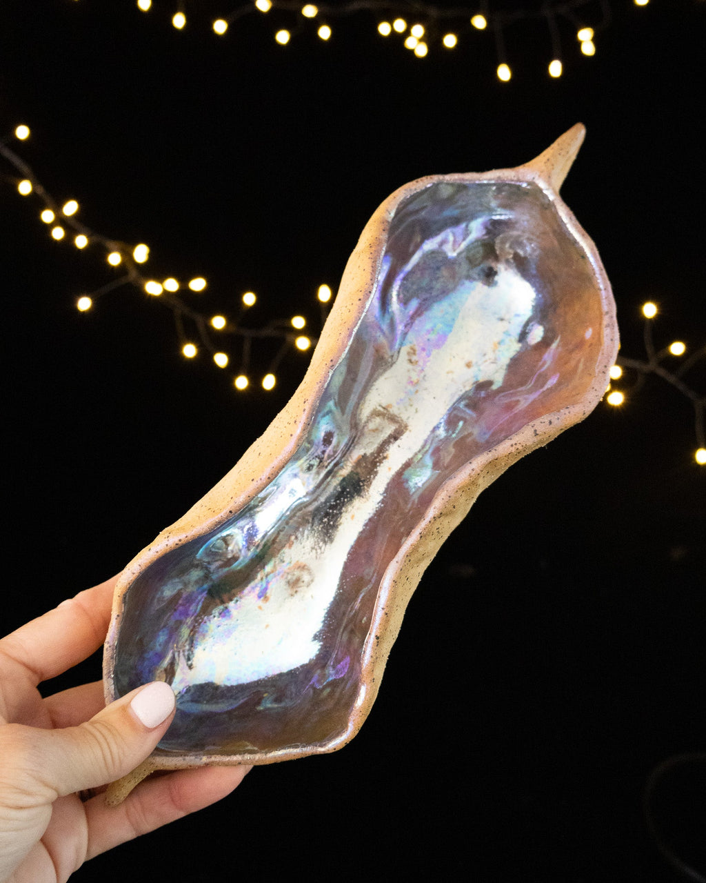 Bare speckled stoneware outside, silvery iridescent luster within the pod