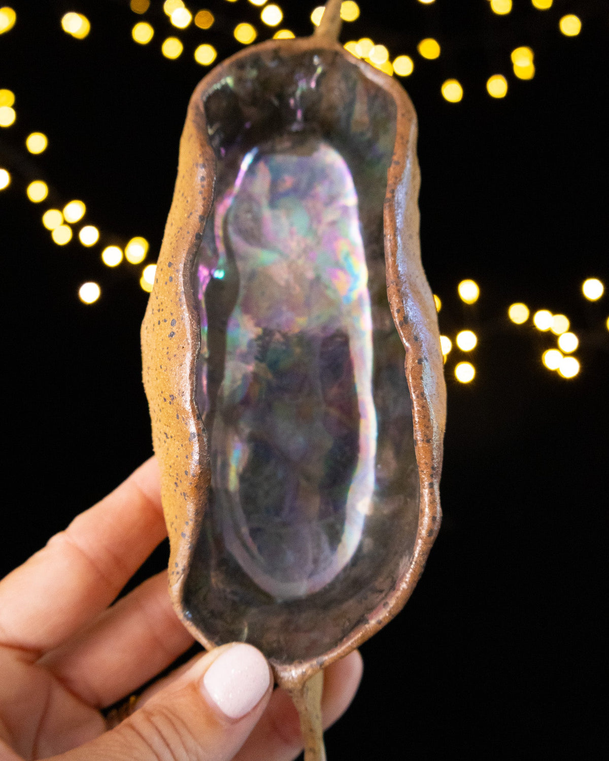 Hand pinched stoneware star seed pod with a cool silver-green luster interior