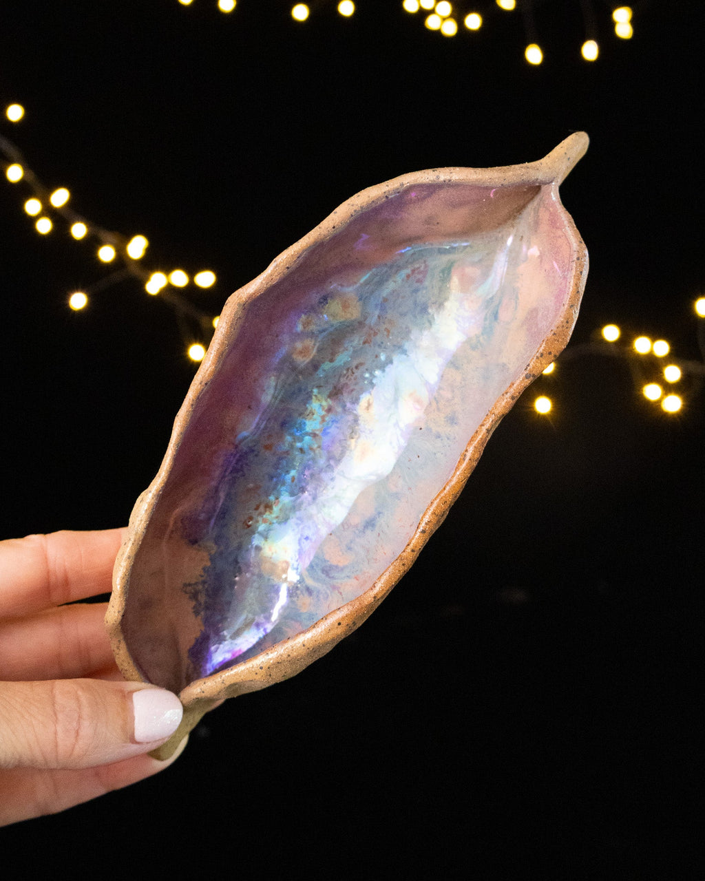 Angled view of a handmade lusterware star seed held in hand