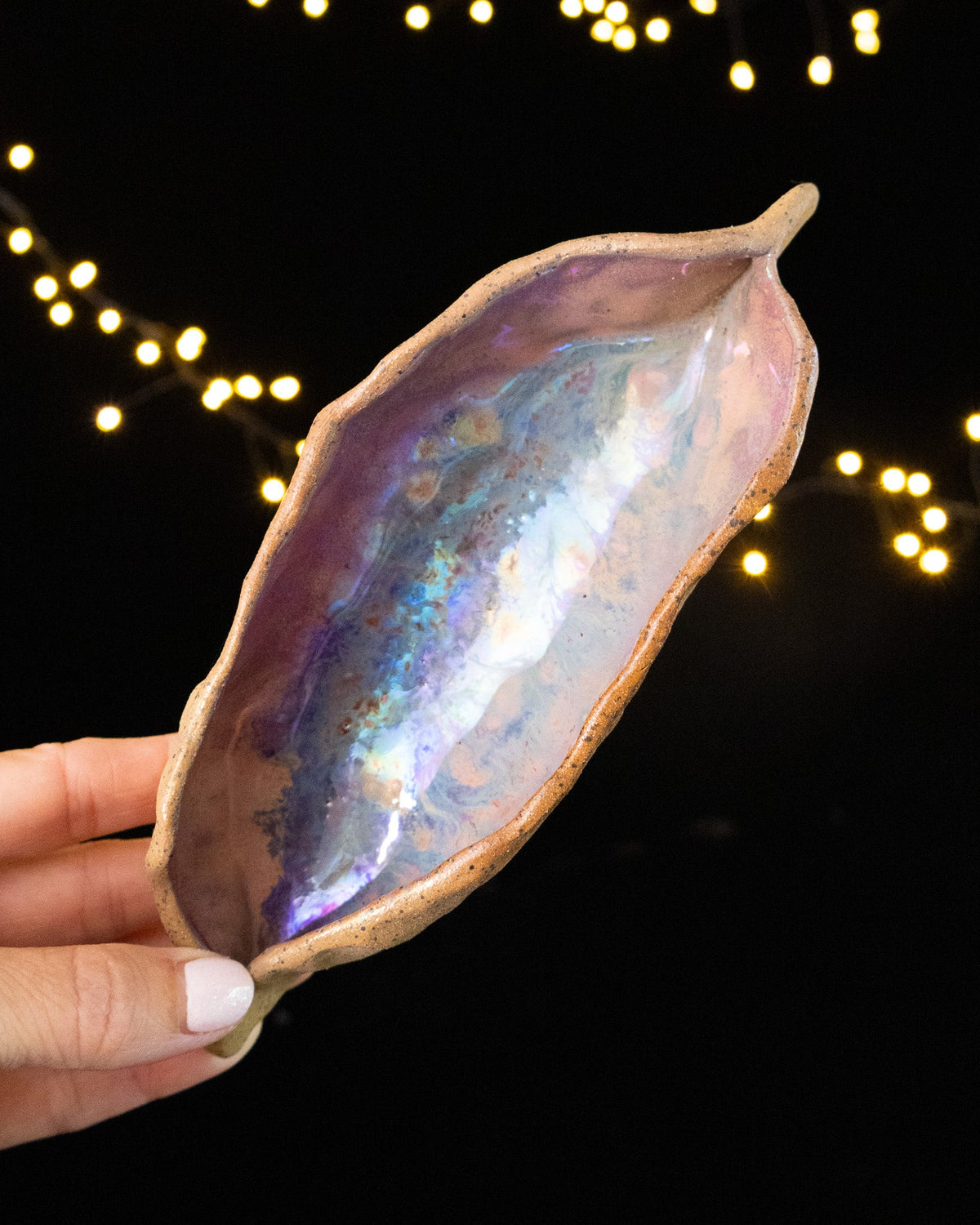 Angled view of a handmade lusterware star seed held in hand