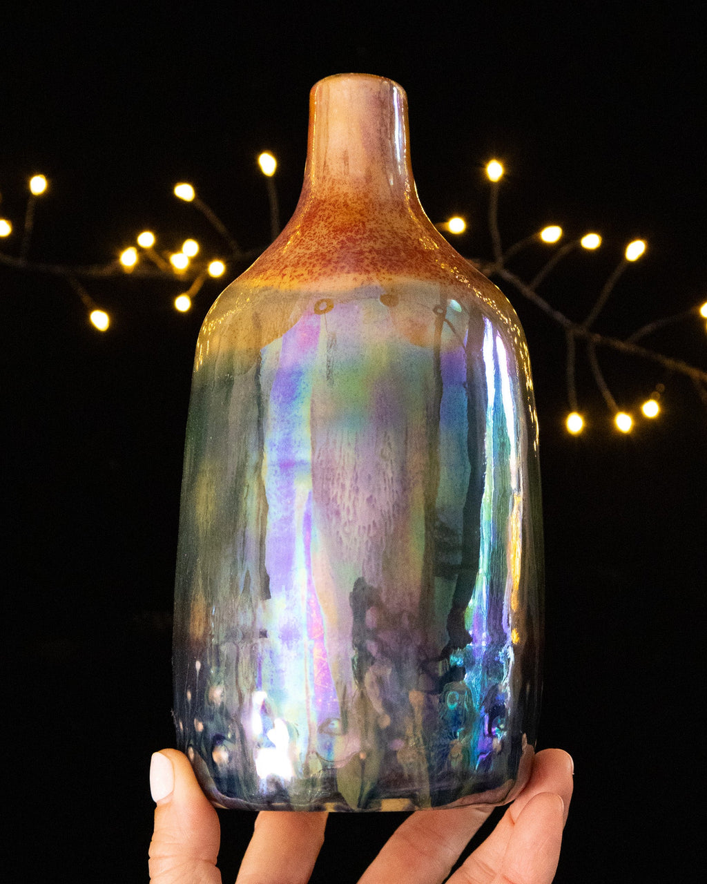 Rust gathering at the shoulder of an iridescent ceramic bottle
