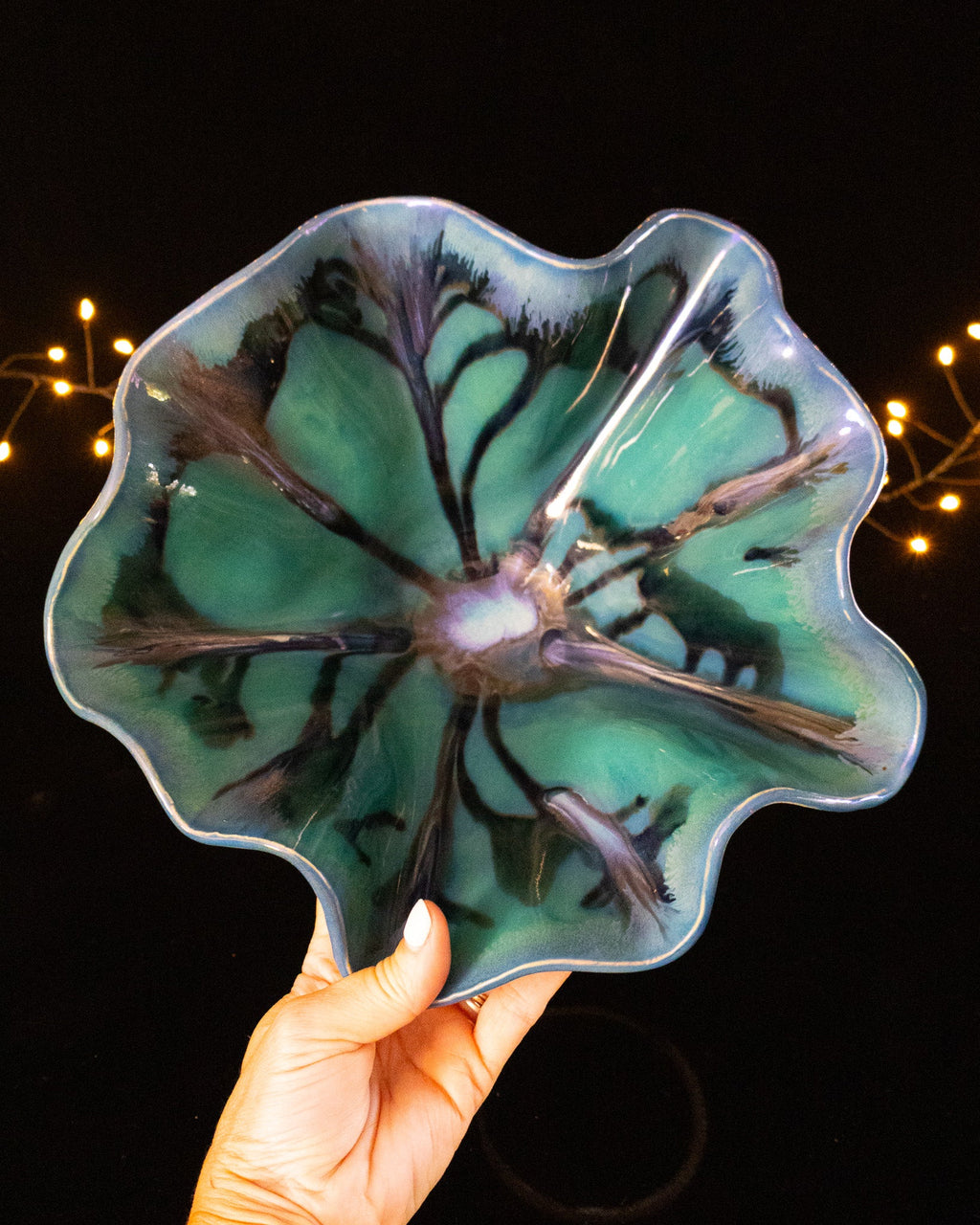 Sea green lusterware bloom sculpture with dark veining, held in hand
