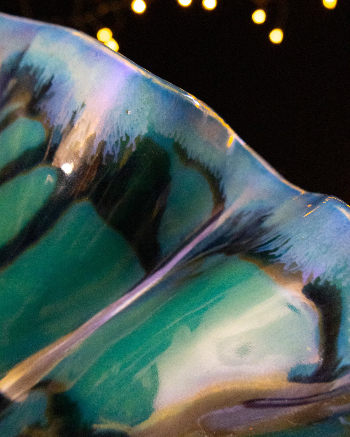Close detail of sea green glaze breaking over the ruffled rim