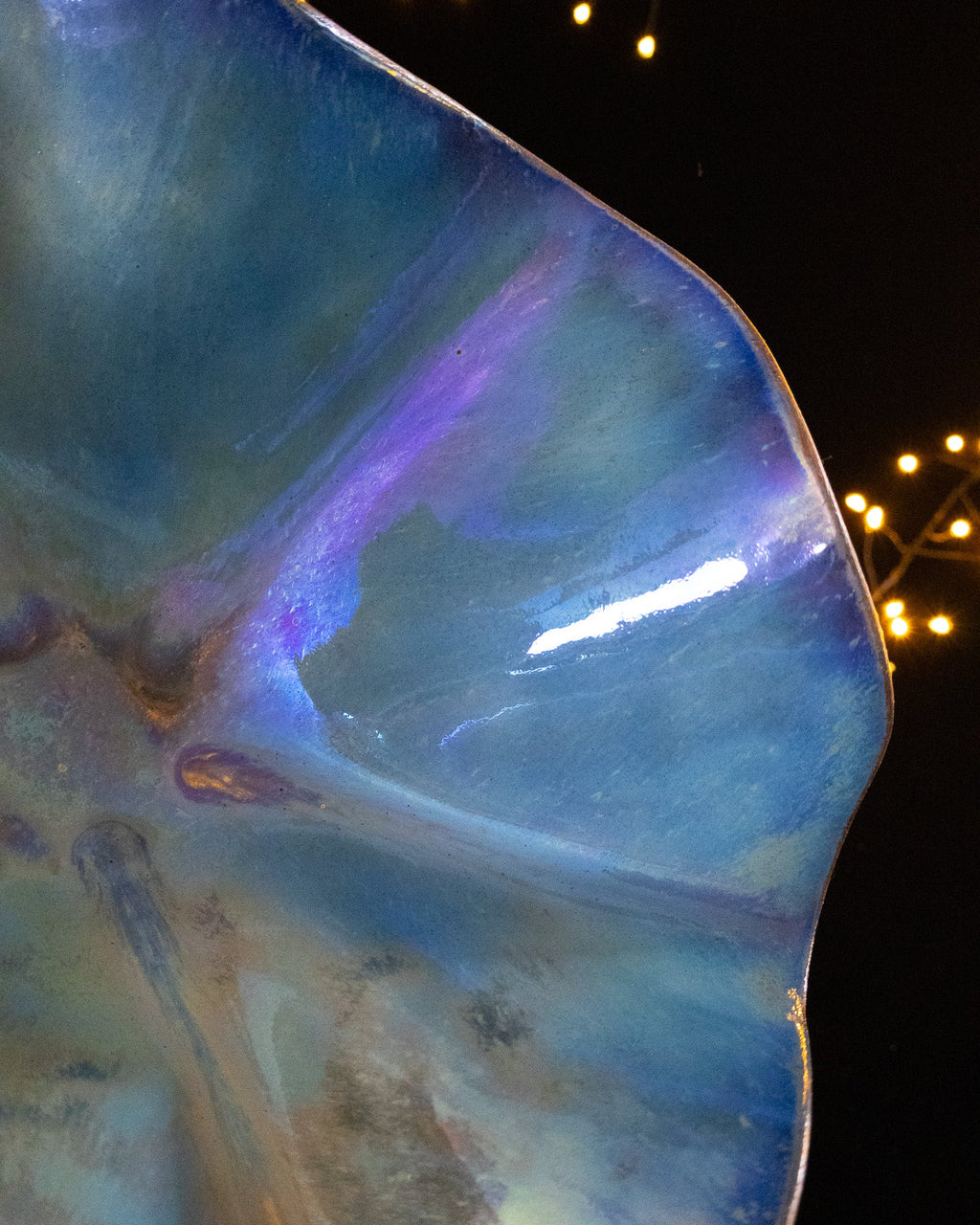 Close detail of violet flaring across a blue lusterware bloom