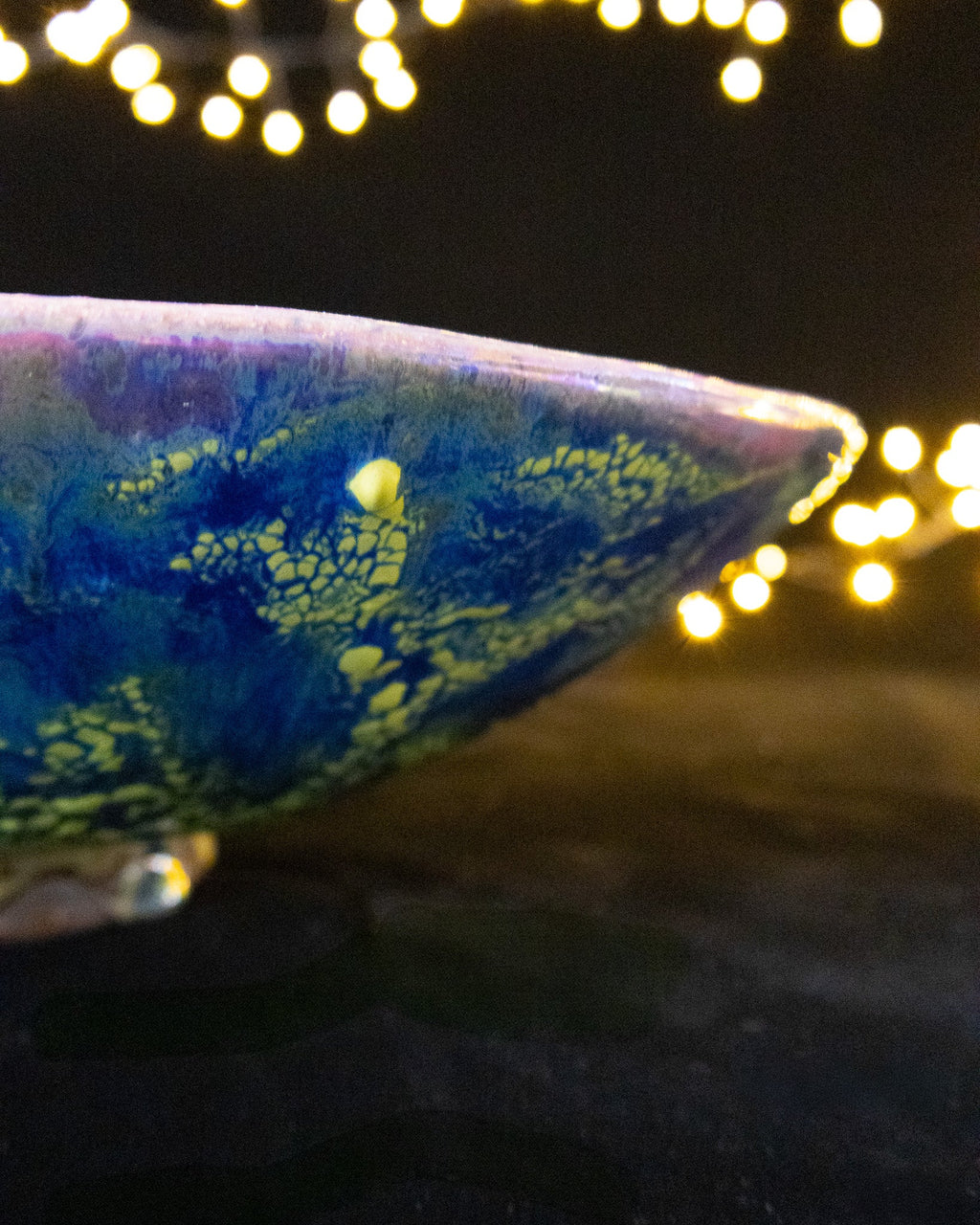 Rim profile of a blue and violet lusterware bowl catching the light