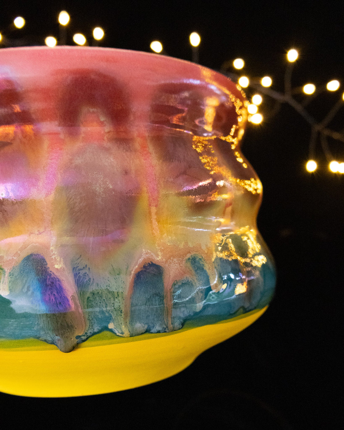 Angled view of a colourful wheel thrown planter with teal drips