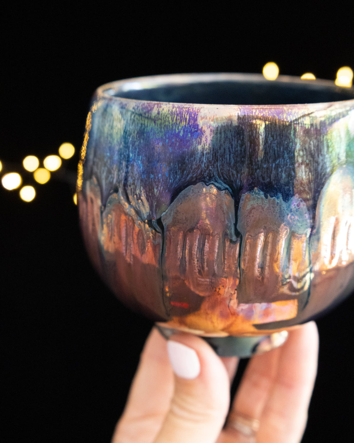 Pale drips running down the body of a handmade iridescent ceramic cup