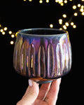 Carved vertical fluting catching the light on iridescent porcelain